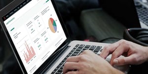 Blog_CloseUpOfMansHandOnLaptopLookingAtHubSpotLeadGenerationReport